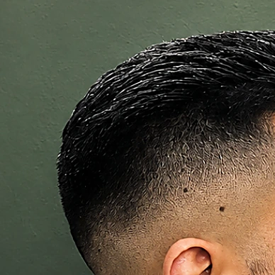 Degradado alto con el cabello corto peinado hacia arriba, visto de lado a la altura de la oreja