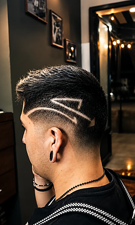 Corte con degradado y un diseño rapado en forma de rayo en la sien, visto de espaldas